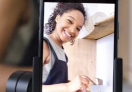 Woman smiling at a smartphone while cooking
